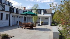 color photo of the terrace at the Timothy Root House looking toward the Root House, showing outdoor table and umbrella