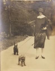 B/w photo of young woman in 1920s dress with 2 dogs on leashes